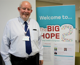 man smiling at camera in front of Big Hope banner